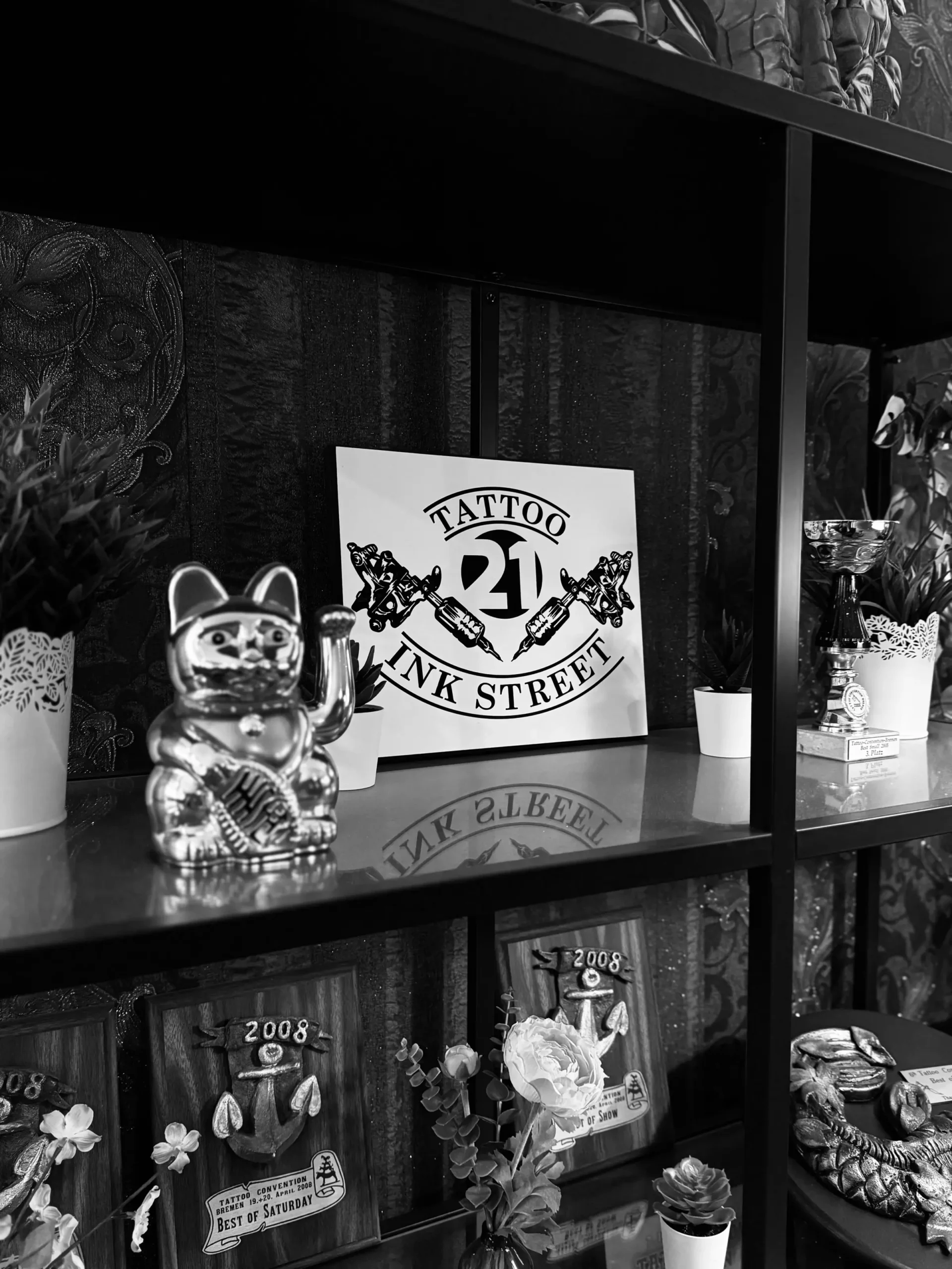 Regal mit Studio-Logo, Winkekatze und Auszeichnungen der Tattoo Convention Bremen 2008