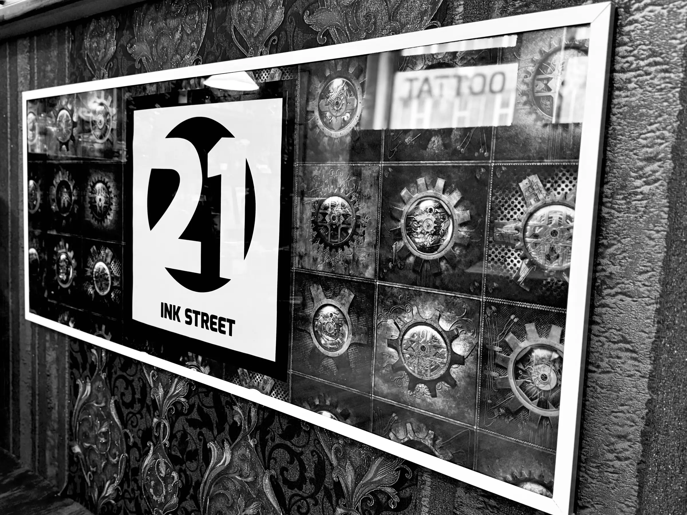 Logo-Schild von 21 Ink Street vor Zahnrad-Tapete